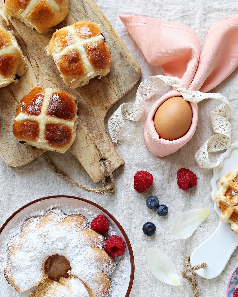 easter festive dessert table with hot cross buns, cakes, waffles and pancakes overhead view