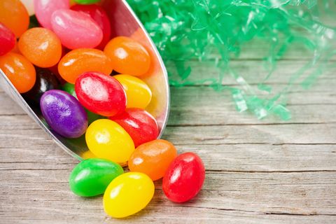 a scoop of colorful jellybeans with decorative artificial grass on an old, weathered wood surface
