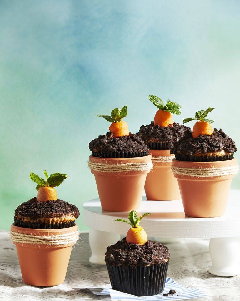 carrot patch cupcakes set inside mini terracotta pots and decorated with crushed oreos to look like dirt and buttercream carrot piped on top