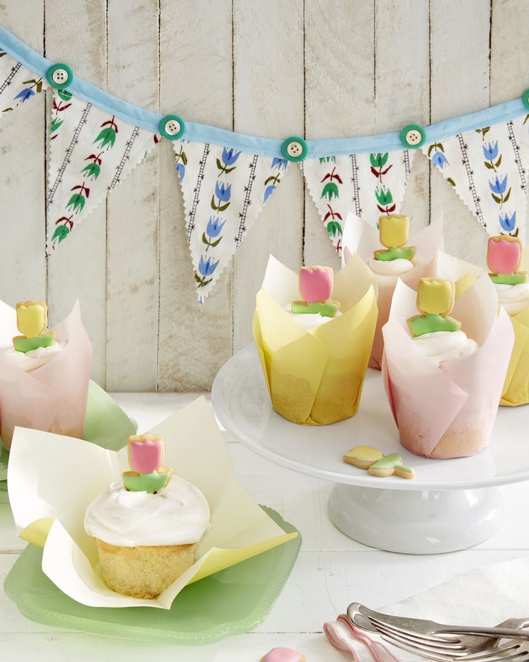 cupcakes with vanilla frosting and mini tulip shaped cookies on top for decoration