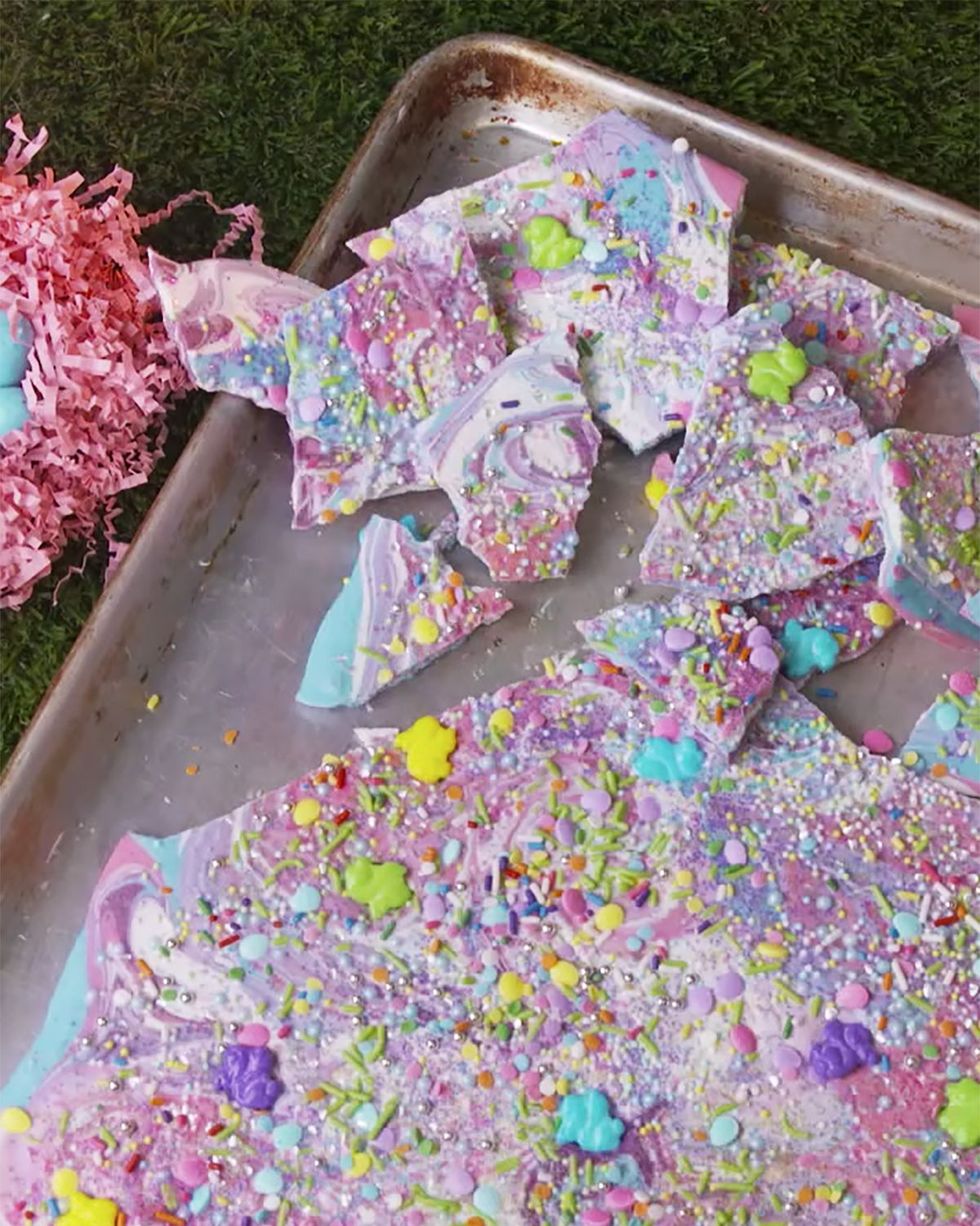 light blue light purple and pink swirled unicorn bark covered in various types of sprinkles and broken into pieces