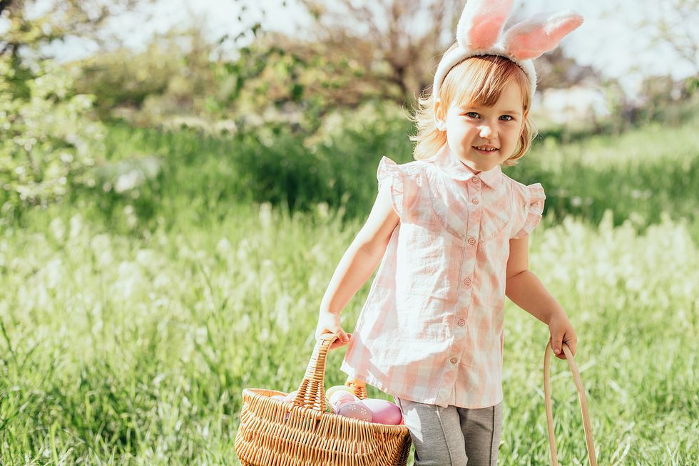 easter egg hunt girl child wearing bunny ears running to pick up egg in garden easter tradition baby with basket full of colorful eggs