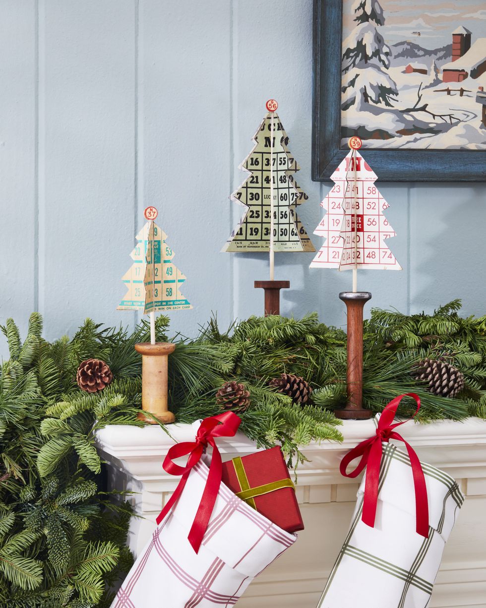 christmas trees made from bingo card set in wooden spools on a mantel