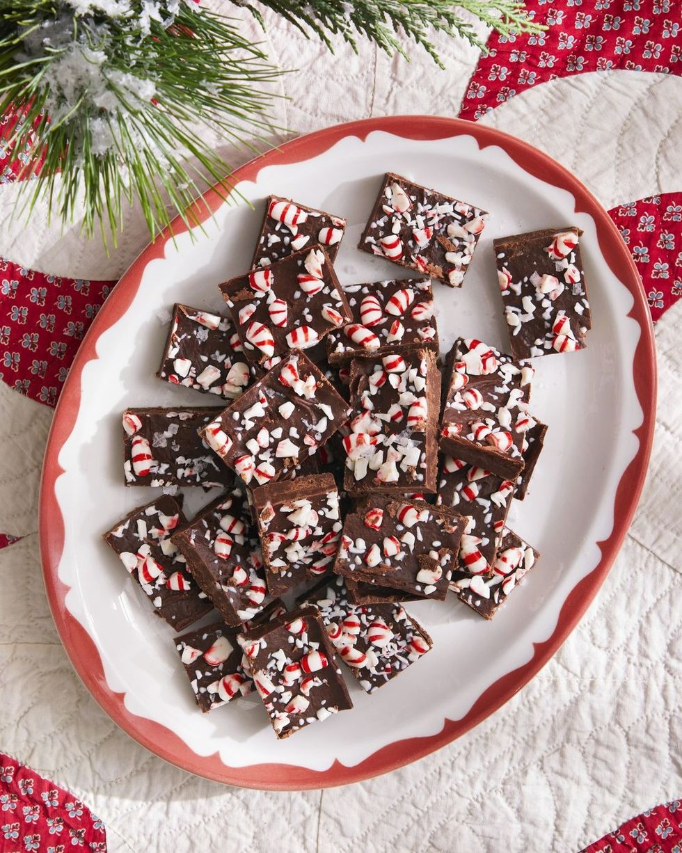 chocolate peppermint fudge cut into squares and stacked on a white oval plate with red trim
