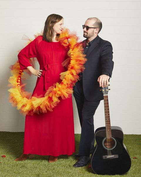 woman wearing red dress and fire hula hoop and man wearing black suit for ring of fire couple costume