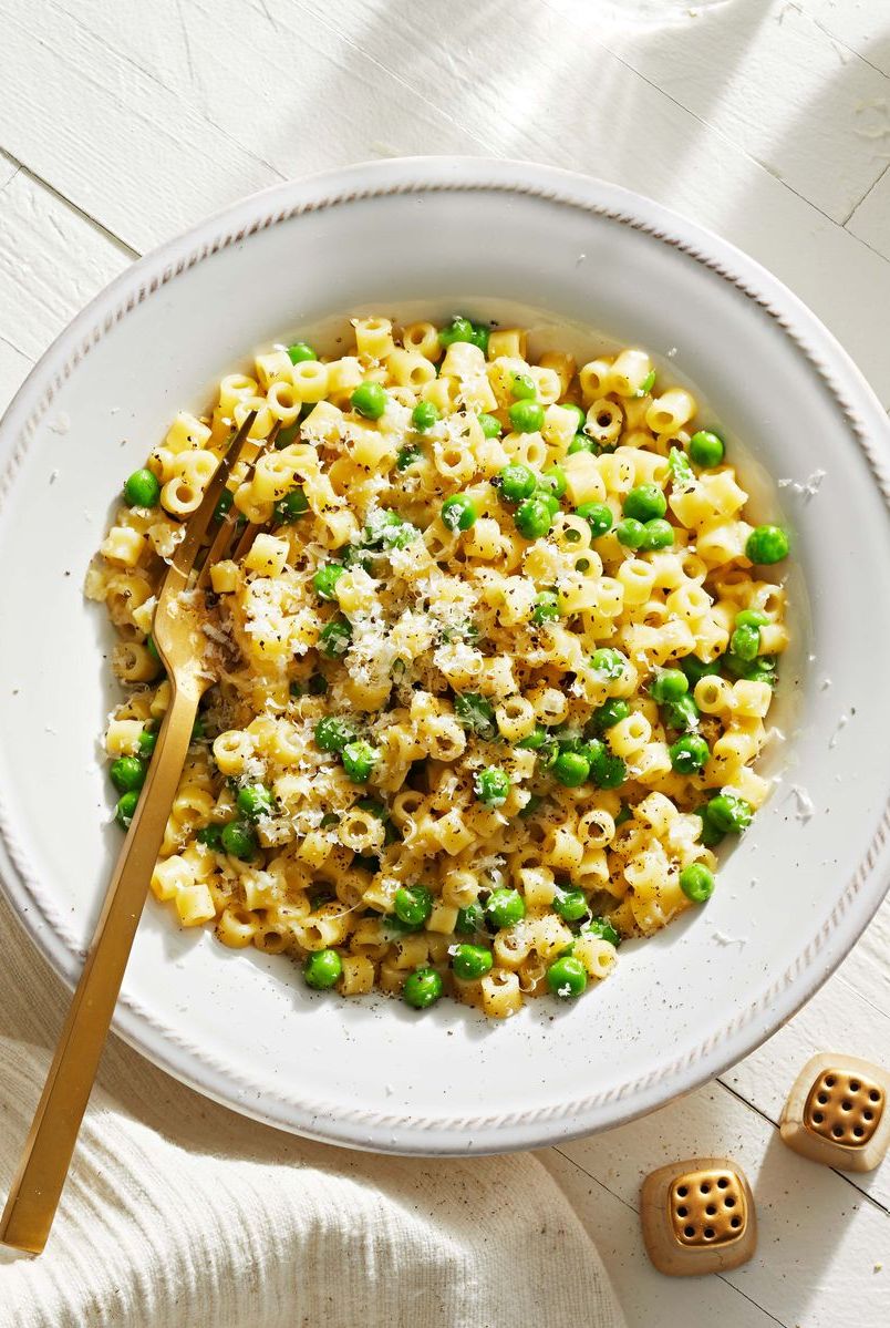 pasta e piselli with green peas on a white plate
