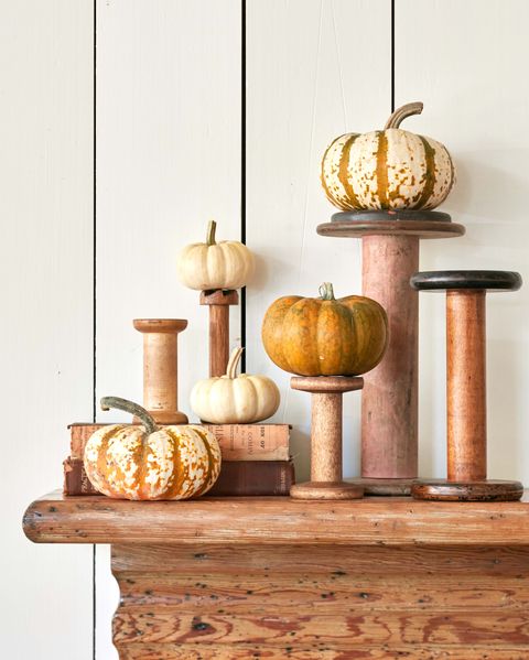 small and mini pumpkins stacked on vintage sewing spools on a wood mantel as an easy diy halloween decoration