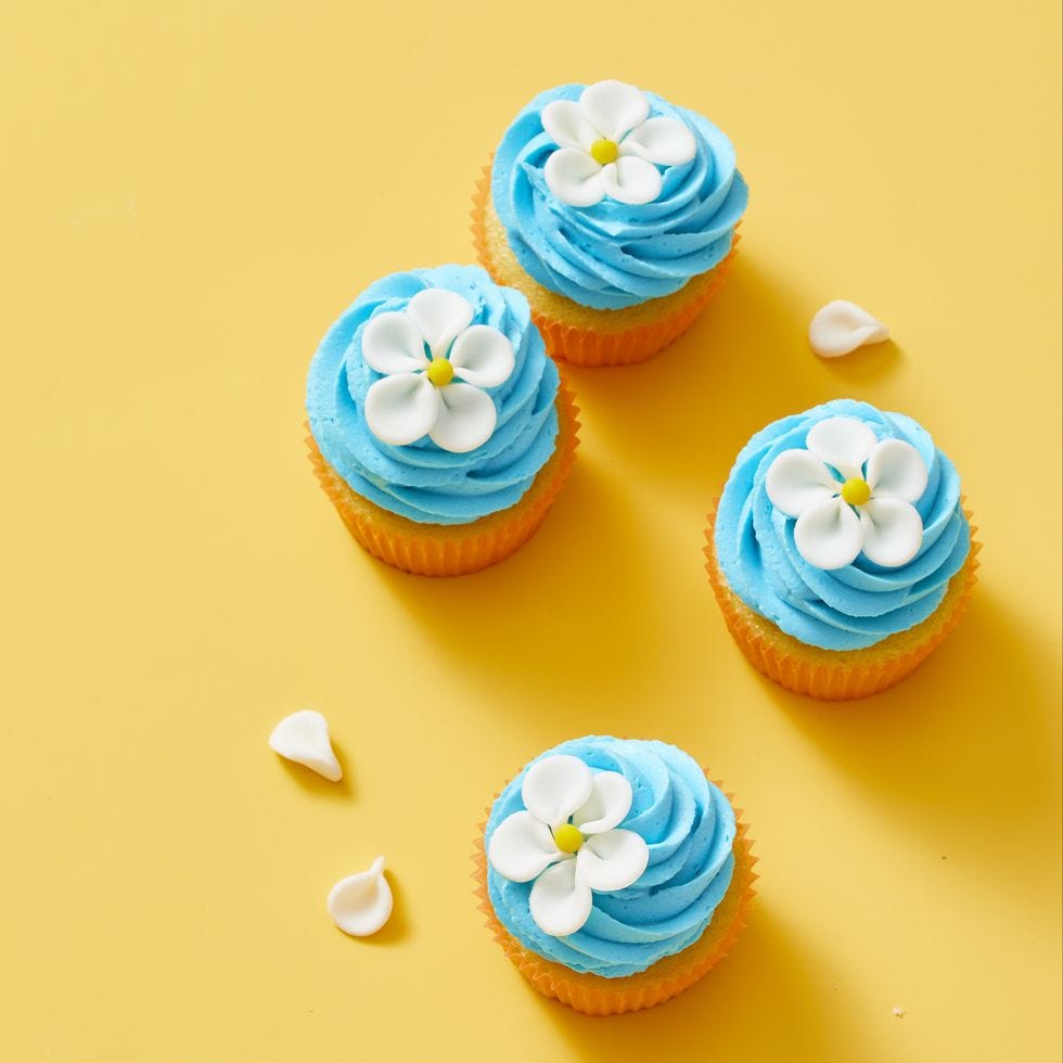 vanilla cupcakes with blue frosting and a white flower on top