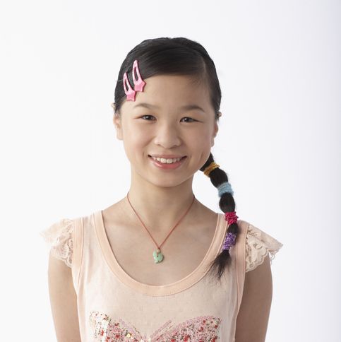 teenage girl smiling and she has two pink hair barrettes on the side and a side ponytail over her shoulder