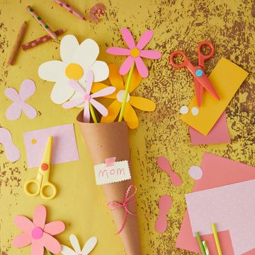paper flowers made from bright pastels on a yellow background arranged in a brown paper cone with a tag that says mom