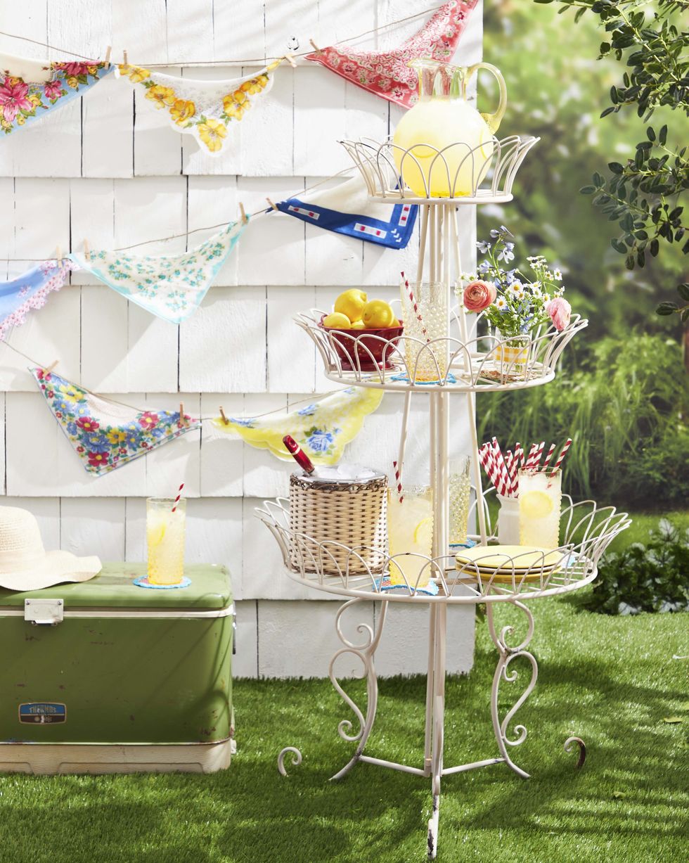 bunting made from vintage hankies hung on an outdoor wall with a tiered lemonade stand in front