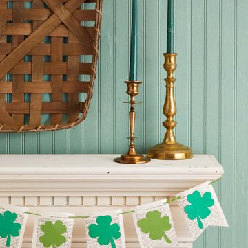 four leaf clover garland made from book pages and green paper hung on an fireplace mantel