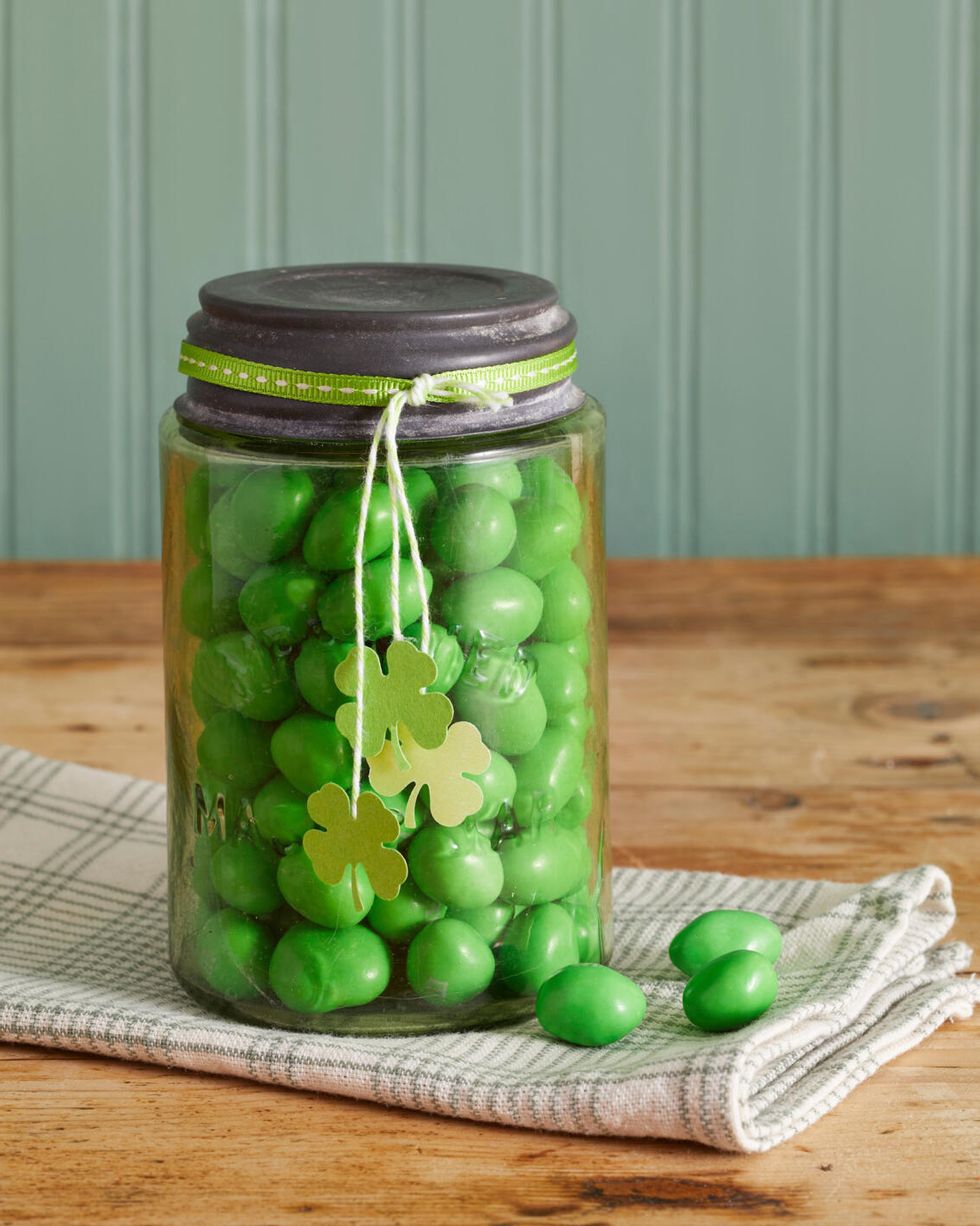 green mason jar filled with green candy and four leaf clover tags hanging on the outside