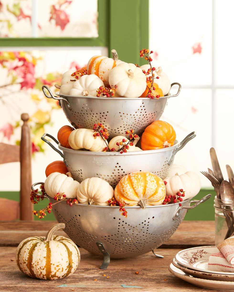 small pumpkins and bittersweet nestled in 3 stacked vintage colanders