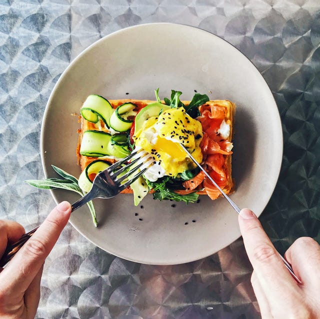 eating brunch with waffle, avocado, cucumber, salmon and poached egg, personal perspective