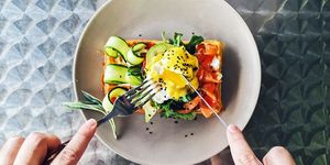 Eating brunch with waffle, avocado, cucumber, salmon and poached egg, personal perspective