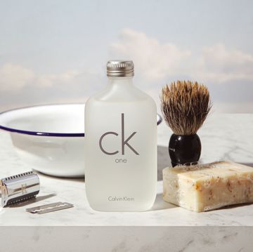 a bottle of ck one and a shaving brush on a table