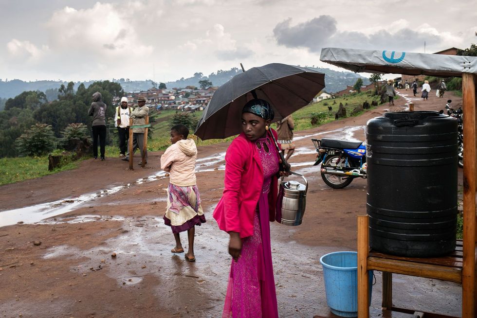 Bij het verlaten van het ziekenhuis in Kyondo wast een vrouw haar handen met chloorwater Aan de rand van de grote steden waar kleine clusters van ebolapatinten zijn aangetroffen heeft de Wereldgezondheidsorganisatie meerdere noodcentra opgezet