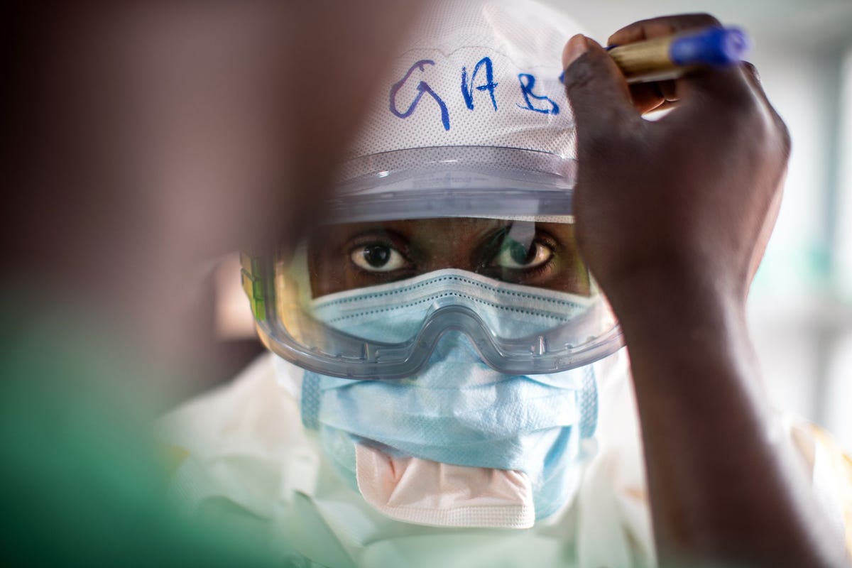 In het doorverwijscentrum voor ebolapatinten in Butembo in de Democratische Republiek Congo DRC trekt een lid van het medisch team zijn beschermende kleding aan Het transitcentrum is momenteel het enige functionerende behandelcentrum voor ebolapatinten in Butembo nadat twee andere centra werden aangevallen en platgebrand