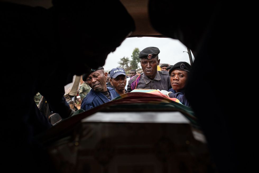 Politieagenten plaatsen de kist van Tabu Amuli Emmanuel 50 in het voertuig waarmee hij van het mortuarium van het Matandaziekenhuis naar de begraafplaats van Butembo wordt gebracht Tabu politieman en vader van zes kinderen werd gedood door gewapende mannen toen hij het behandelcentrum voor ebolapatinten van Mdecins Sans Frontires trachtte te beschermen