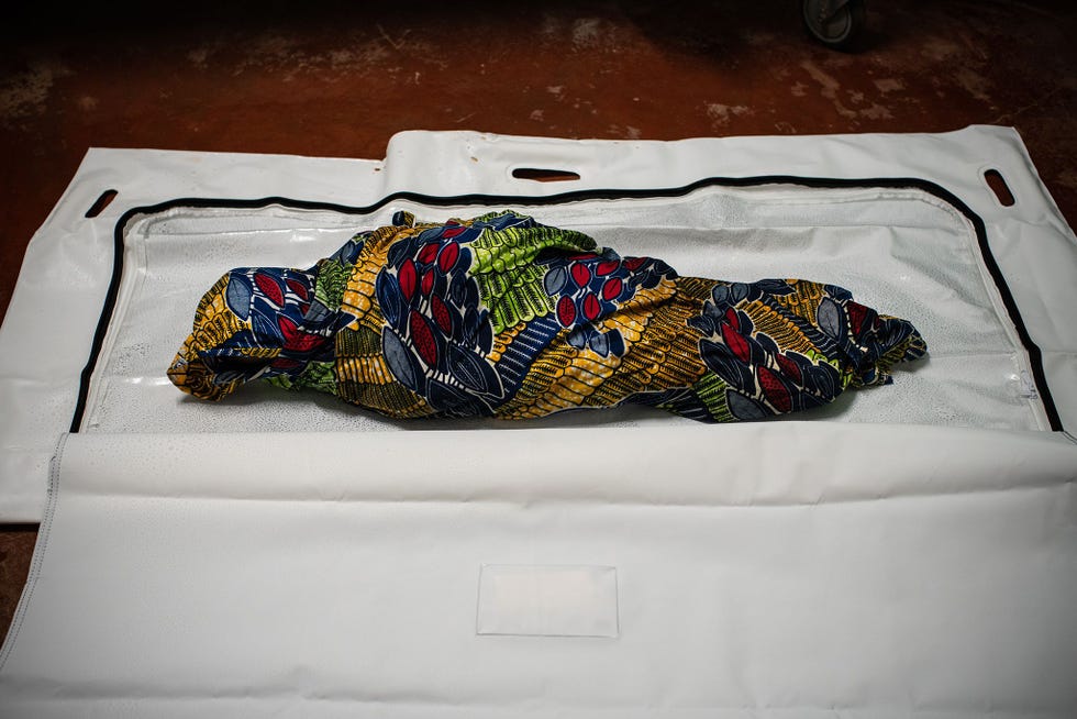 In het algemeen ziekenhuis van Kyondo in de DRC bereiden gezondheidswerkers het lichaam van een jong meisje voor op een veilige maar waardige begrafenis door haar familie Het meisje overleed kort na aankomst in het ziekenhuis en werd postmortem als ebolaslachtoffer gediagnosticeerd waardoor haar doodsoorzaak bij het maken van deze foto nog onbekend was Omdat Kyondo een halfuur van de dichtstbijzijnde stad ligt en de binnenkomst van testresultaten vaak wordt vertraagd hebben in de afgelopen maanden alle patinten die hier zijn overleden een veilige en waardige begrafenis gekregen ongeacht de doodsoorzaak Het op veilige manier begraven van ebolaslachtoffers is van groot belang voor het indammen van de epidemie want het lichaam van een overleden patint is nog steeds zeer besmettelijk