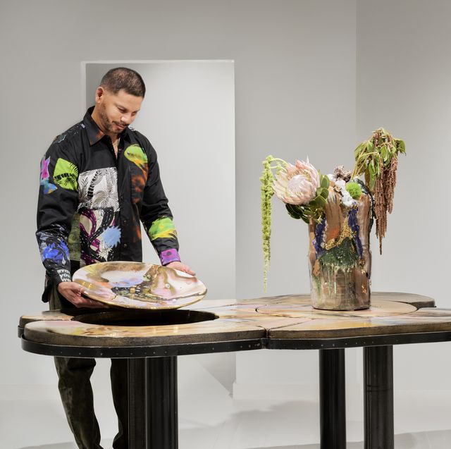 reinaldo sanguino standing a ceramic bowl table and vessel with a stool and artwork in the background