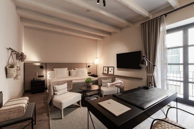 Modern hotel room with a sleeping area and workspace.