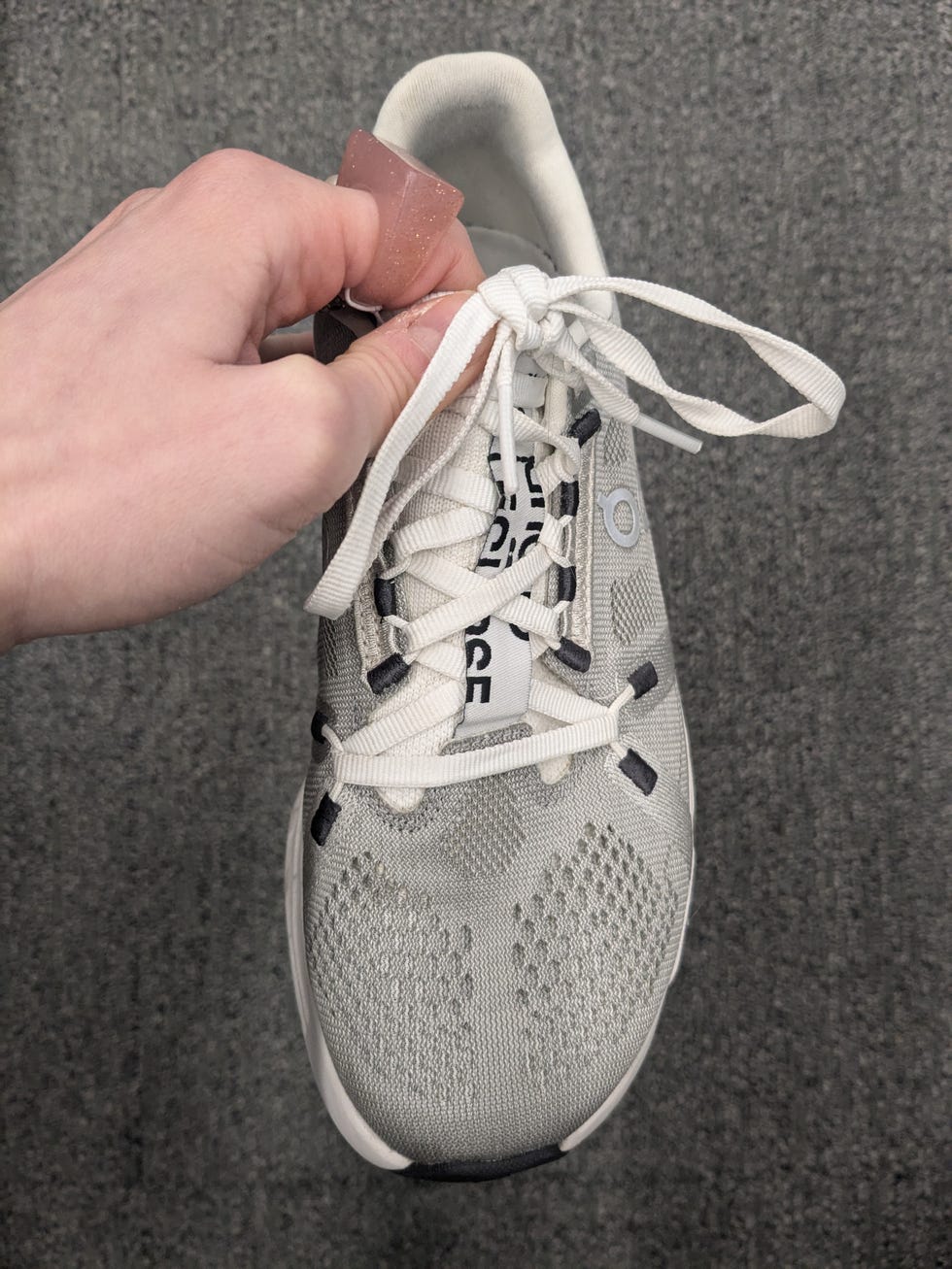 a hand holding a sneaker with laces being tied