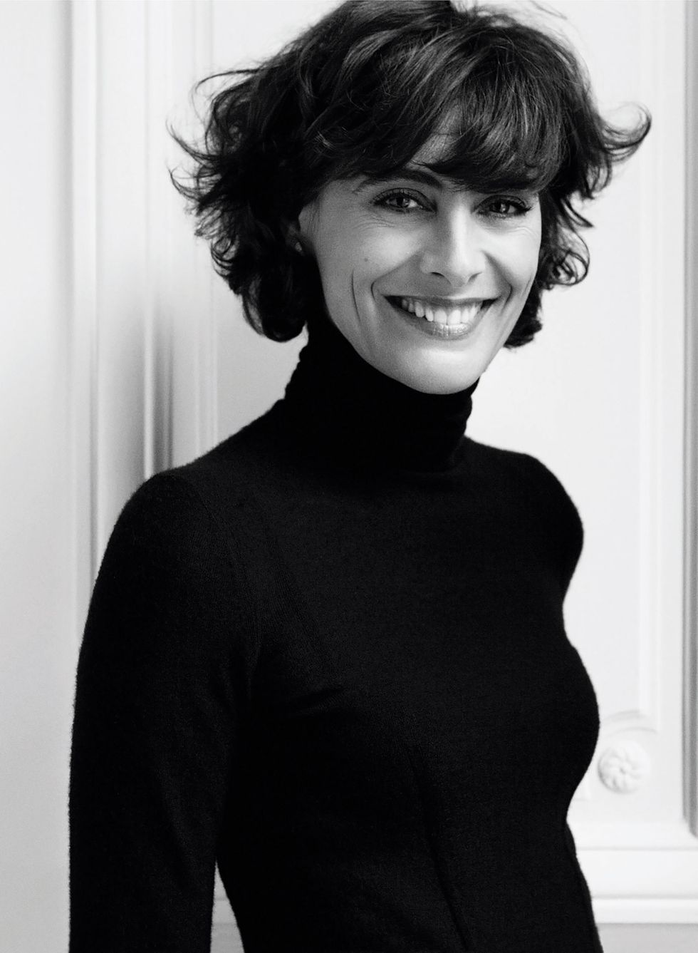 lovely woman with a black turtleneck and dark hair smiling into the camera