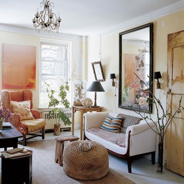 in the living room of decoupage artist john derians lower east side apartment a vintage boat fender is sued as an ottoman and the sisal rug is from abc carpet and homethe large mirror is early 20th century french from rooms and garden and the photograph golden screen is by derian friend jack pierson