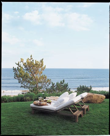 two wooden chaises with white cushions outside on the lawn