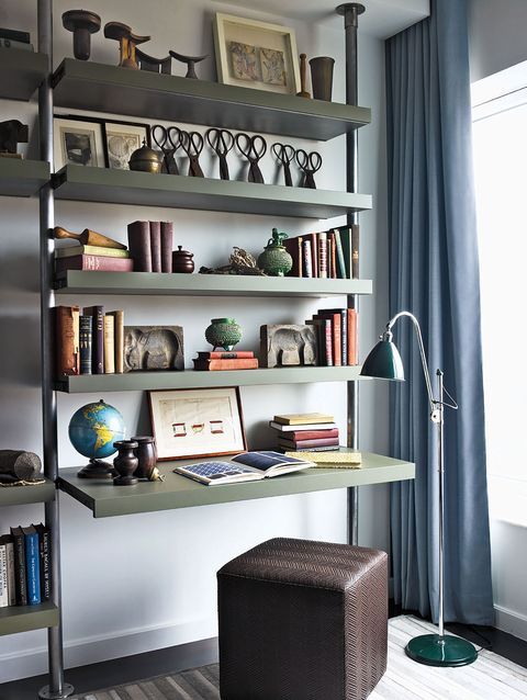 Un lampadaire de Design in Hand se trouve à côté d'une étagère en métal et bois faite sur mesure, un pouf de Calvin Klein Home