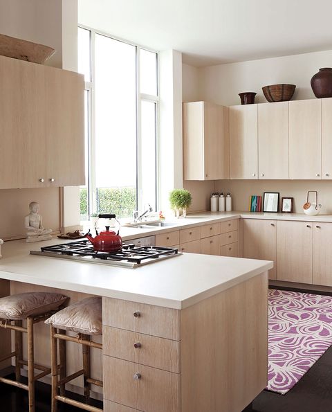 modern whitewashed oak kitchen furniture with a white worktop and a colorful white and lilac designer rug on dark wooden floors