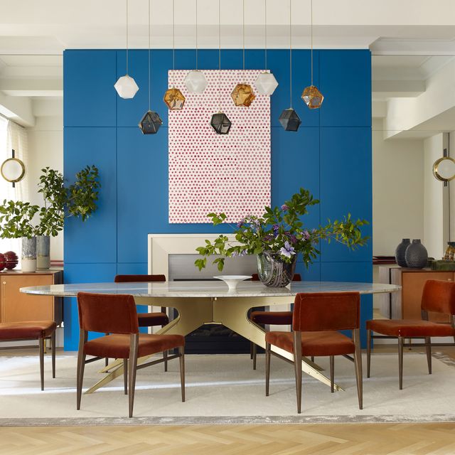 dining room with bright blue fireplace a mid century modern table and rust colored dining chairs designed by nicole fuller