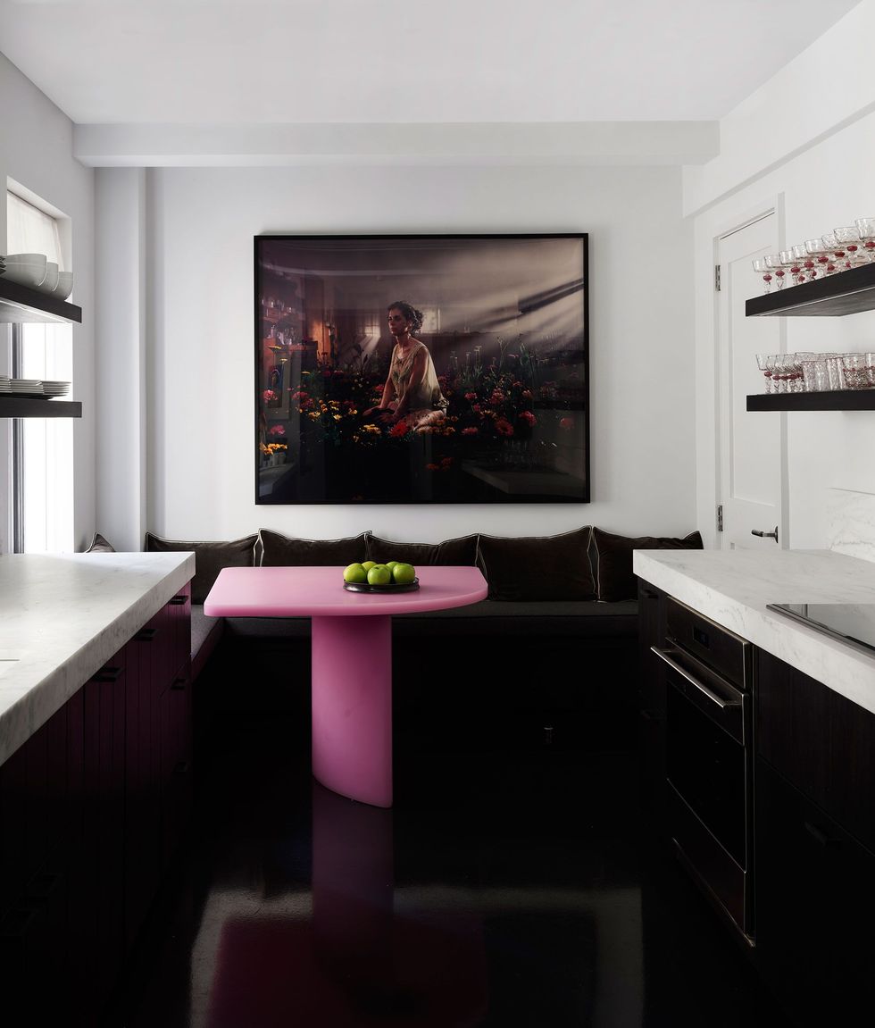 a kitchen white white walls and countertops black cabinets and a pink table