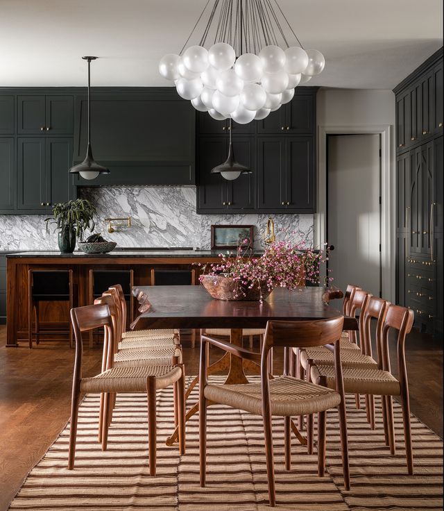 a kitchen with black cabinets a large wooden table and dining chairs