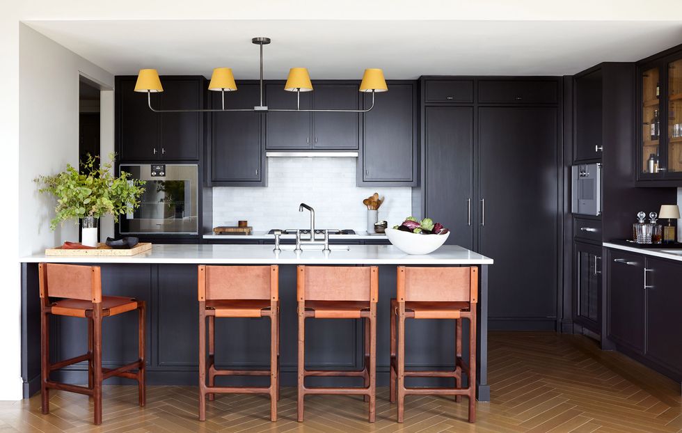 a kitchen with all black cabinets and bar stools