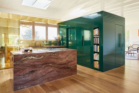 green lacquered cube hold appliances next to an island in pink marble
