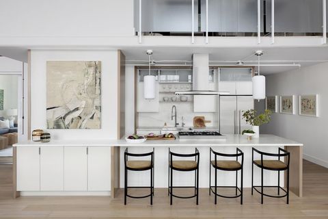 open white kitchen with counter, stools, and pendant lights