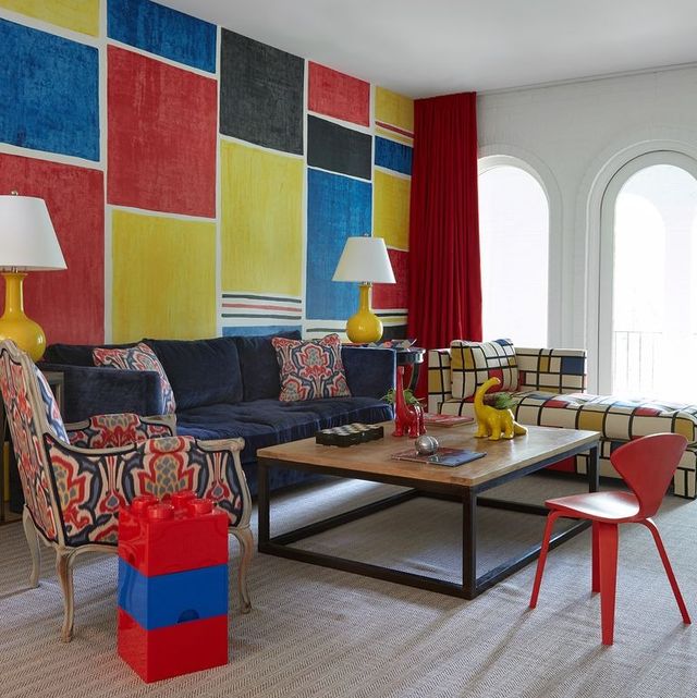 colorful living area with matisse inspired chaise and blue sofa and blue and red wing chair with a lego side table and colorful block painting on the wall behind