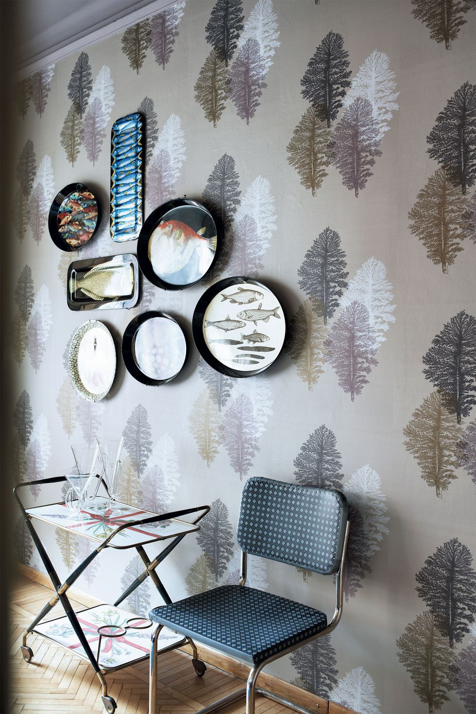 wall with metallic looking wallpaper with abstract leafy print and a blue char and trolley