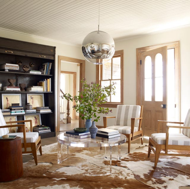 living area with lucite cocktail table and delicate armchairs with white and ecru vertical stripes and a large round pendant overhead