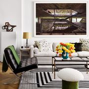 living area with white sofa black leather and chrome quilted armless chair green pouf with white fuzzy top that looks like a mushroom geometric black gray and white rug a glass table and a large modern artwork over the sofa