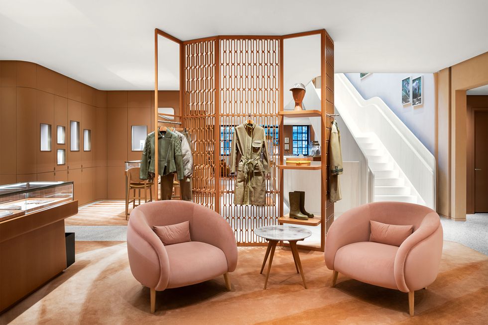 store set up with two rounded velvety pink armchairs with a tall cut out screen behind it and a white staircase off to the right