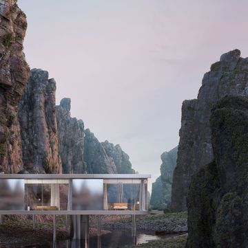 futuristic glass home set in a valley gorge with high mountains around it and a river below