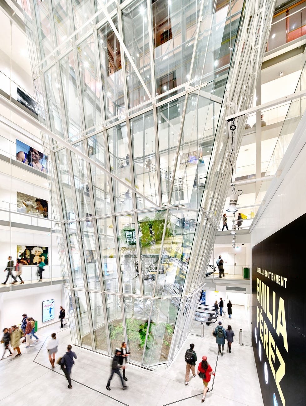 modern atrium of a building with glass structure and people moving through