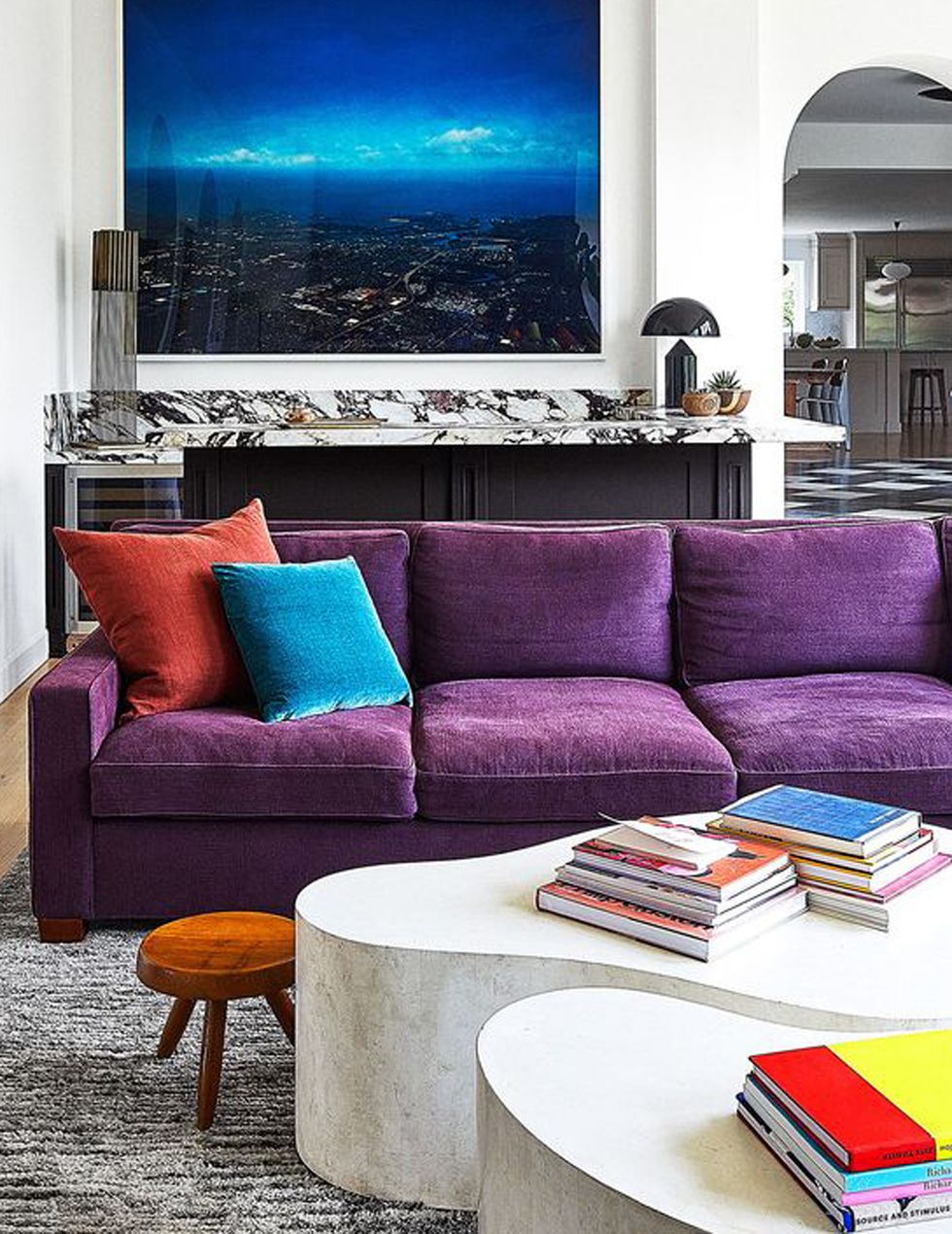 room with large tv on wall and purple sofa at center