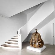 in the entry hall a mirror polished bronze pumpkin by yayoi kusama is framed by a swooping white plaster staircase