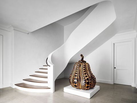 in the entry hall a mirror polished bronze pumpkin by yayoi kusama is framed by a swooping white plaster staircase