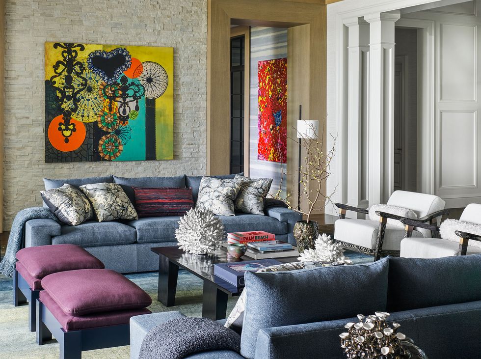 in the living room are two sofas, two benches, and two armchairs surrounding a square cocktail table, and two colorful wall artworks